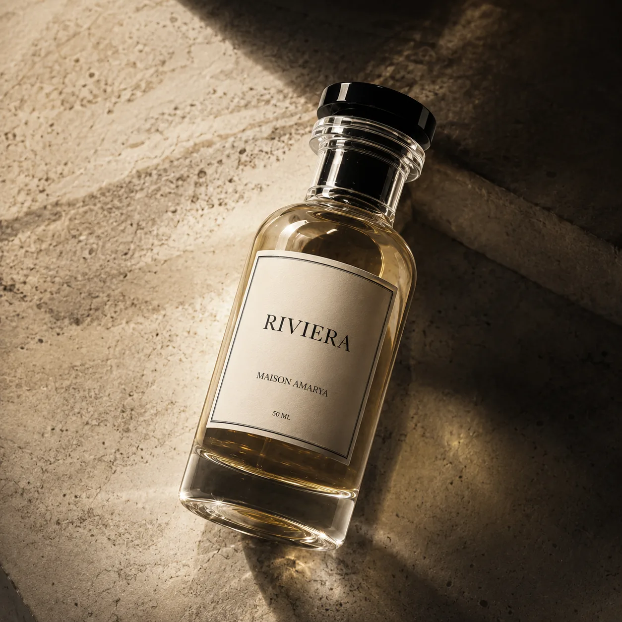 Gros plan du flacon d’extrait de parfum Riviera et de son étiquette, sur un marbre veiné.